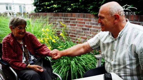 Sven Koppehel im Gespräch mit einer Bewohnerin, dabei hält er ihre Hand und lächelt.